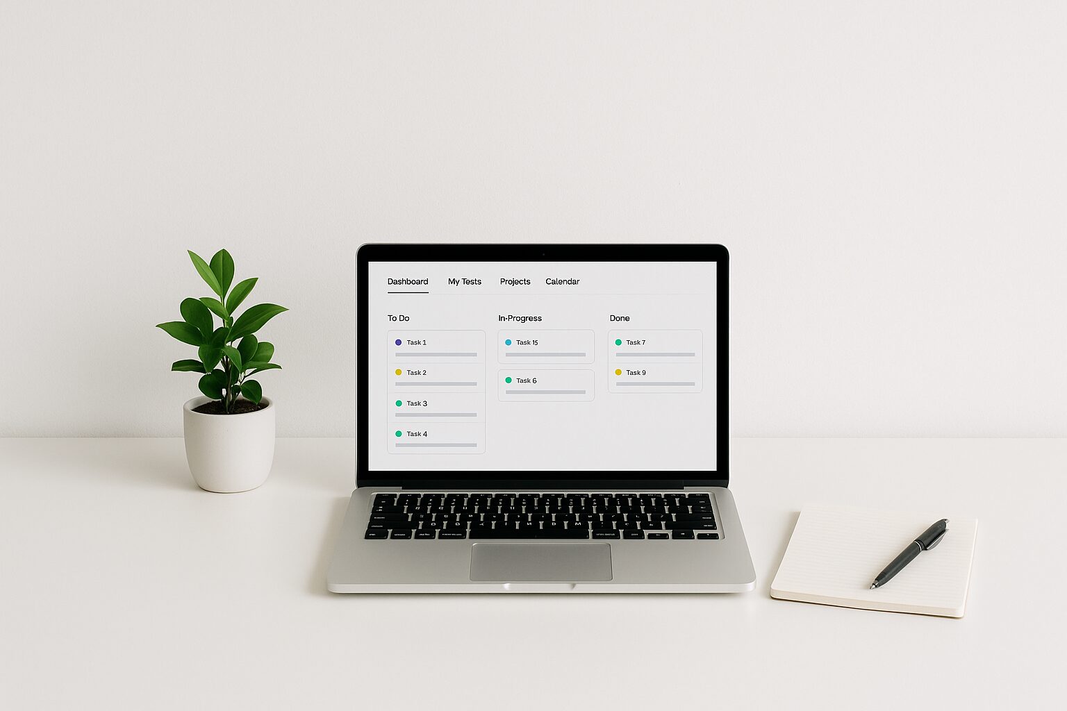 A minimalist workspace featuring a clean white desk with a laptop open to a project management dashboard. A small potted plant adds a touch of greenery, while a notepad and pen lie neatly beside the laptop, symbolising productivity and organisation.